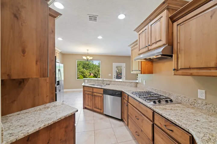 Kitchen featuring light stone counters, stainless steel appliances, light tile patterned floors, a peninsula, and a chandelier