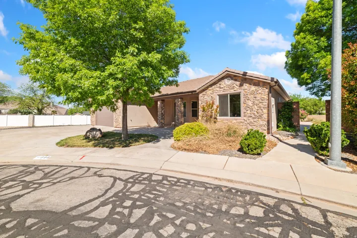 Ranch-style house featuring stone siding, concrete driveway, and stucco siding