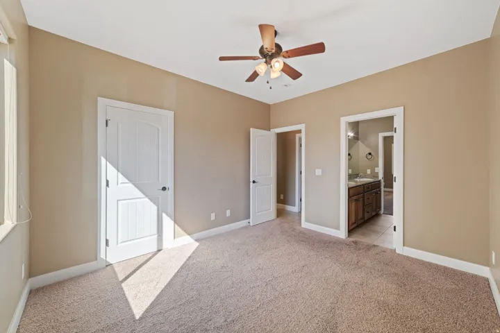 Unfurnished bedroom with light colored carpet, a ceiling fan, and ensuite bathroom