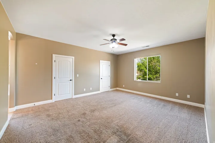 Master bedroom featuring light carpet and ceiling fan