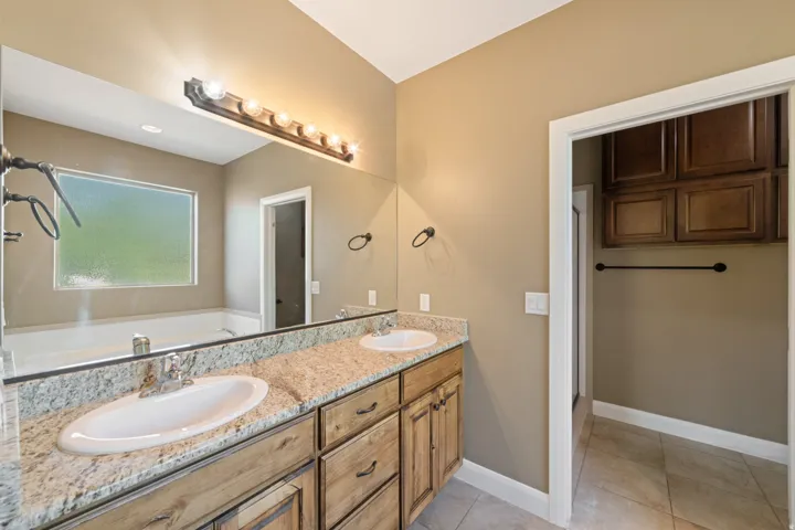 Bathroom with double vanity, light tile patterned floors, and a bath