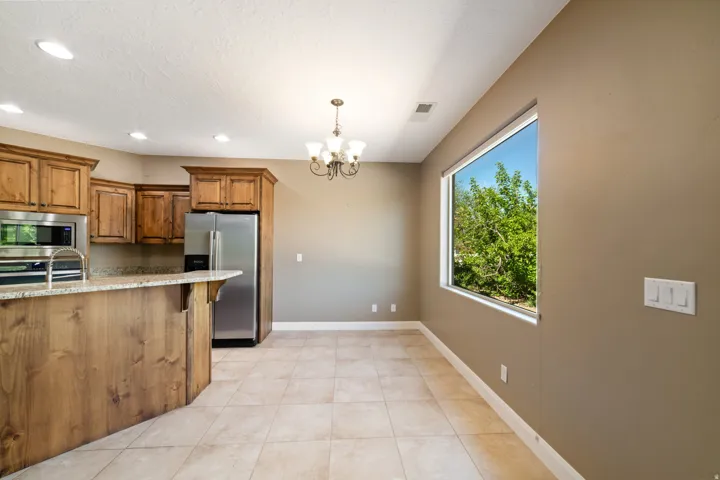 Kitchen featuring wood finish cabinets, suspended lighting, stainless steel appliances, a breakfast bar, and light stone counters