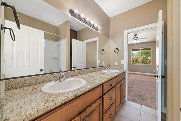 Full bath featuring double vanity, a shower, and light tile patterned flooring