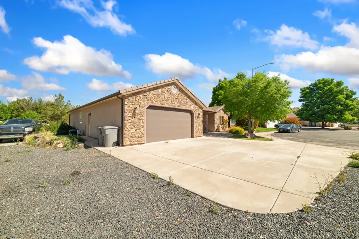 View of property exterior featuring stone siding, concrete driveway, and a garage