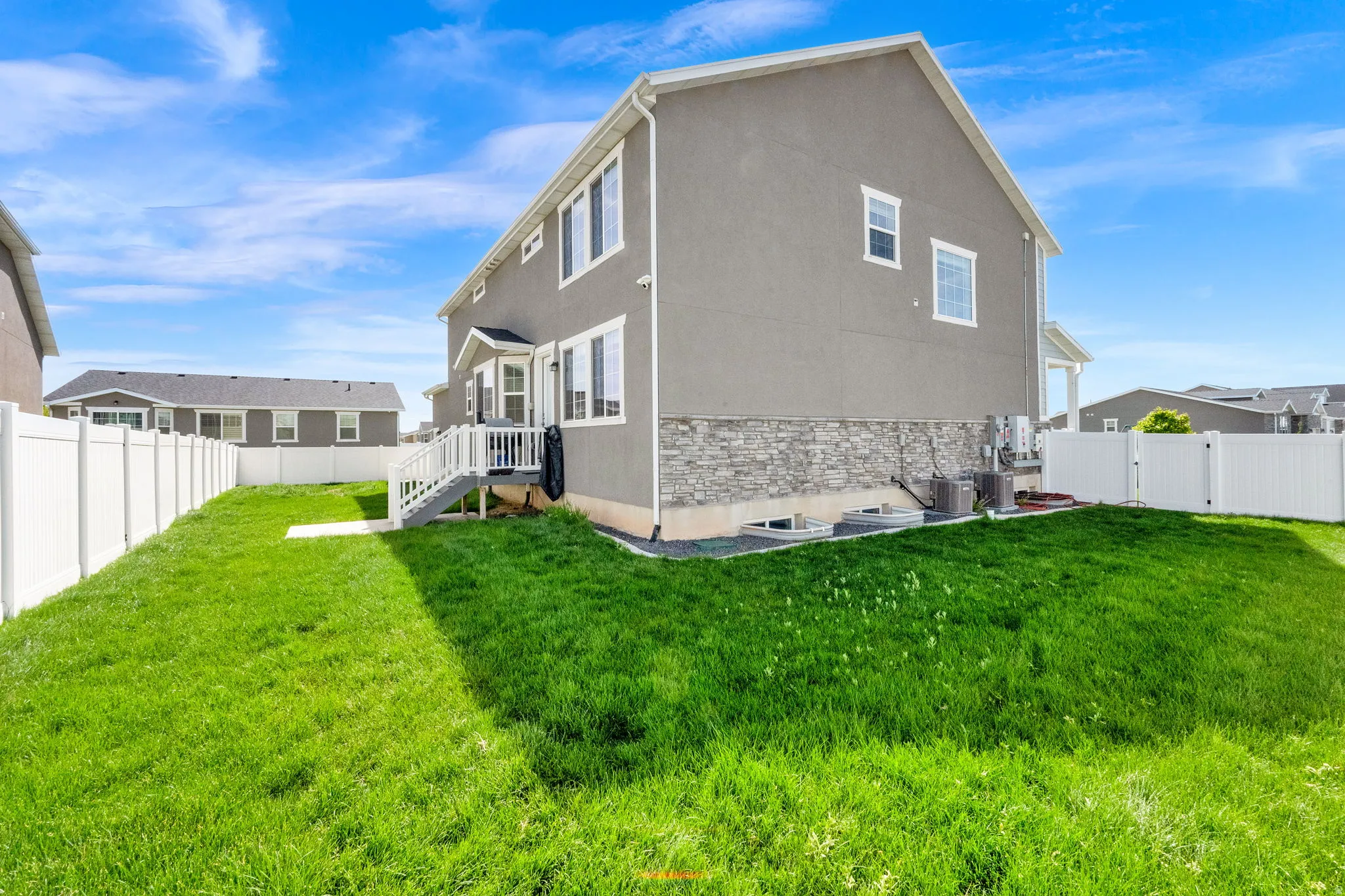 Rear view of property featuring stone siding, a fenced backyard, stucco siding, and a gate
