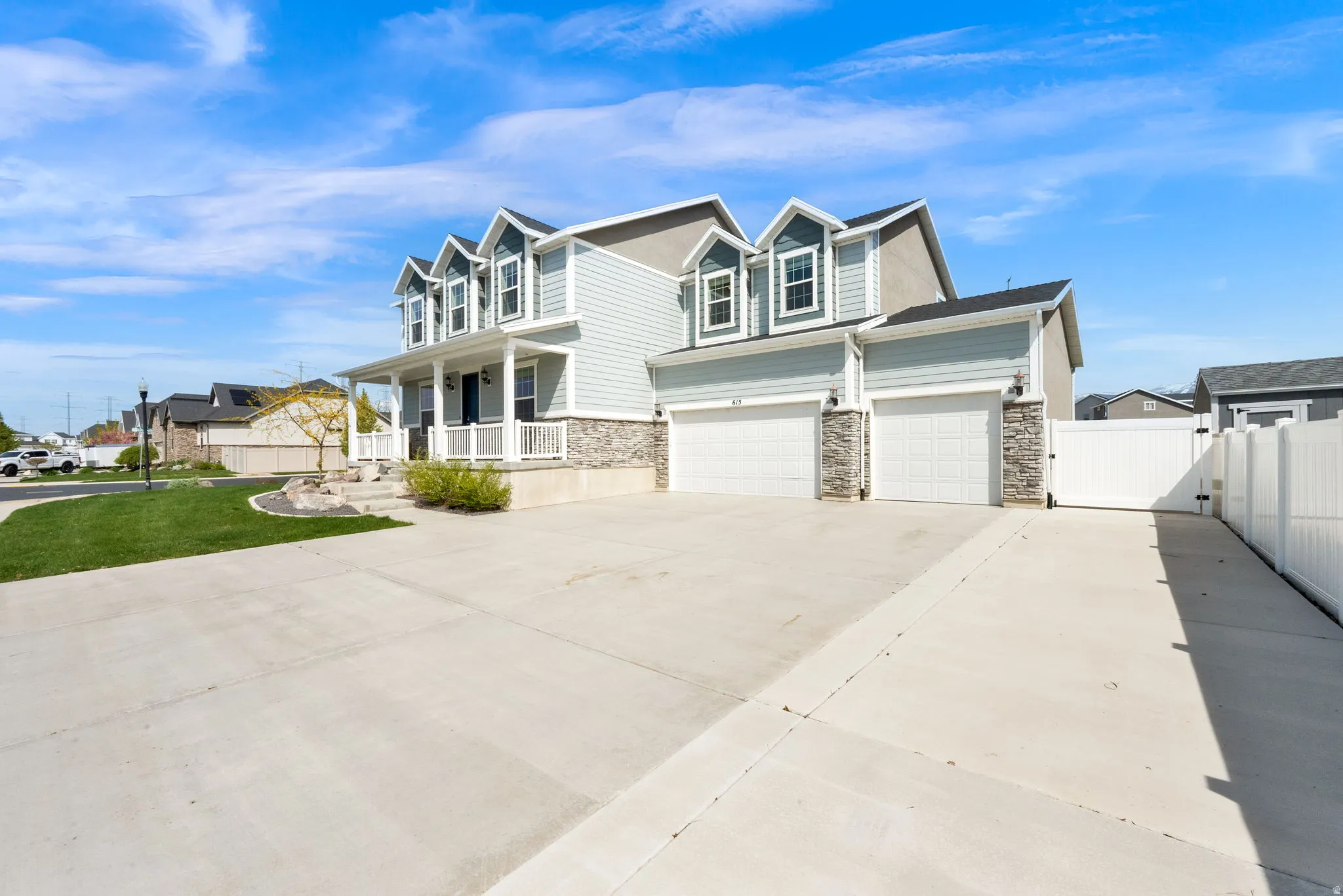 View of front of house featuring covered porch, a gate, driveway, and stone siding