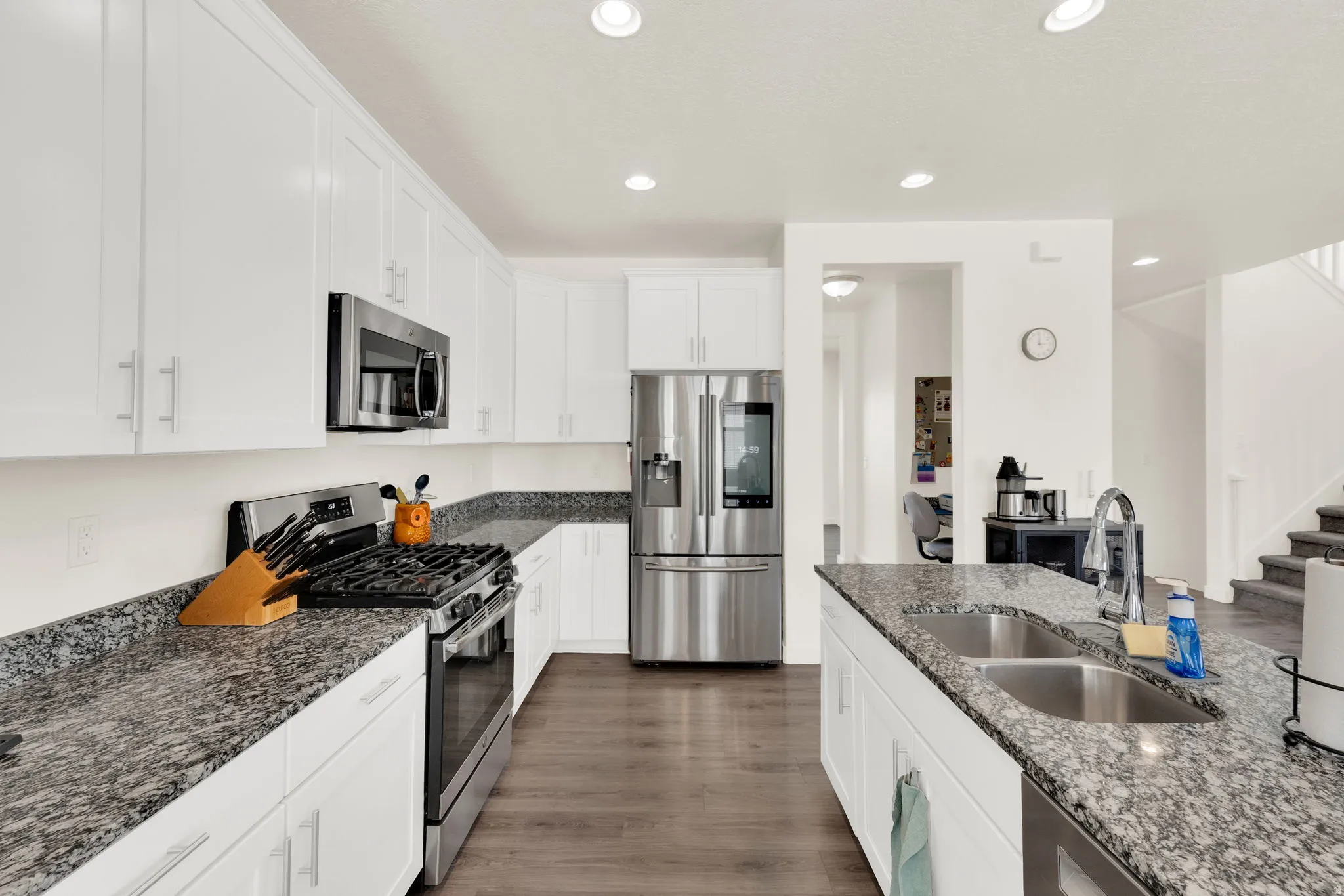 Kitchen featuring stainless steel appliances, white cabinets, dark stone countertops, dark wood finished floors, and recessed lighting