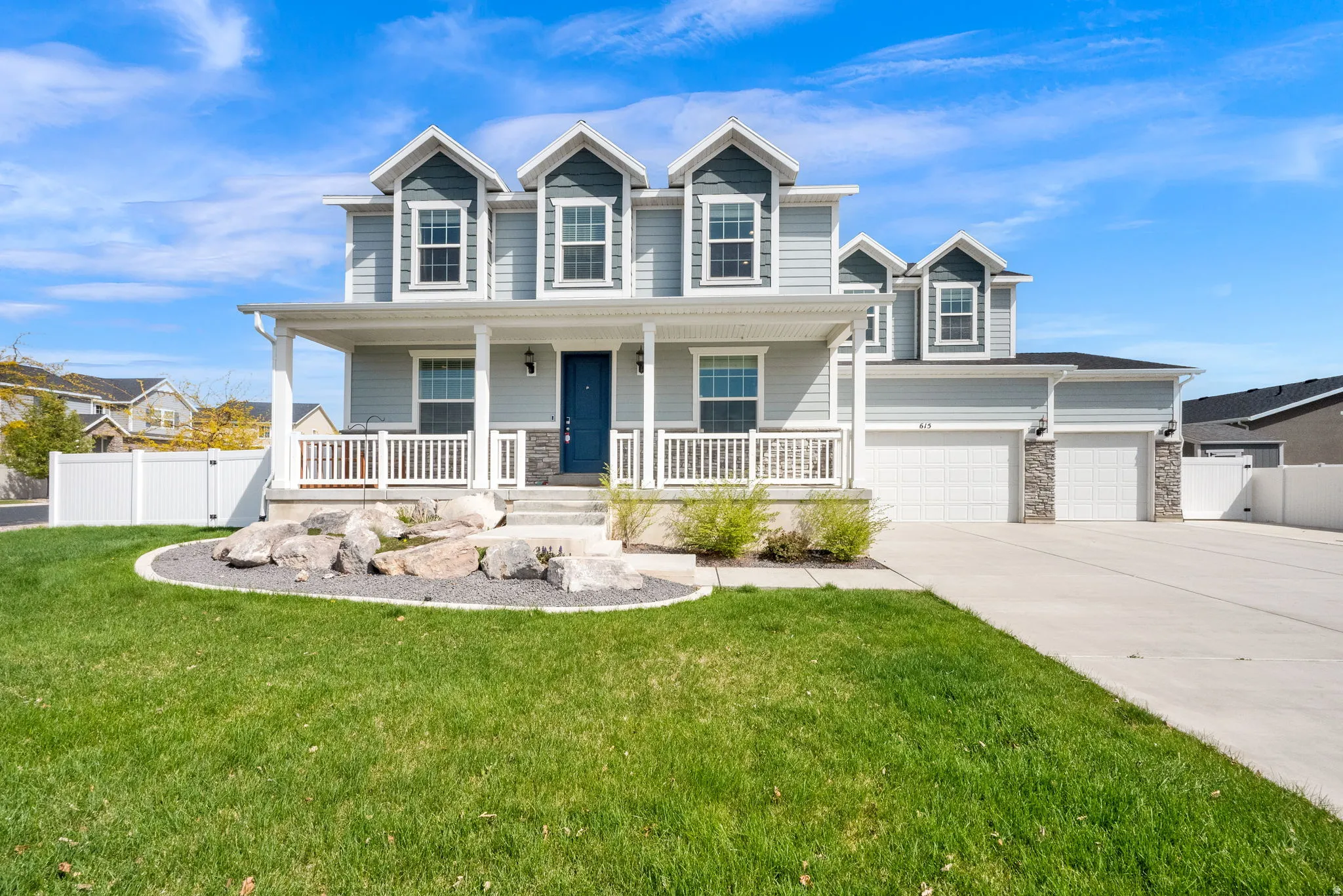 View of front of home featuring a gate, stone siding, covered porch, driveway, and an attached garage