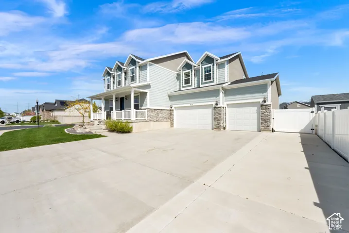 View of front of house featuring covered porch, a gate, driveway, and stone siding