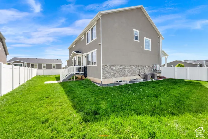 Rear view of property featuring stone siding, a fenced backyard, stucco siding, and a gate