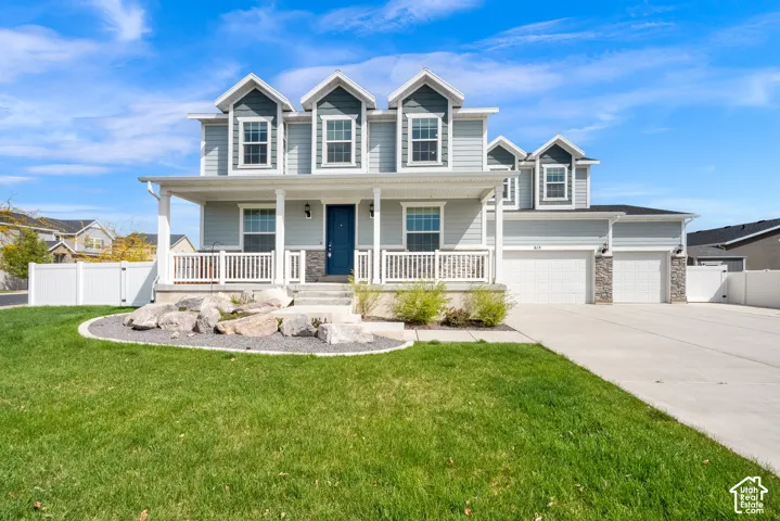 View of front of home featuring a gate, stone siding, covered porch, driveway, and an attached garage