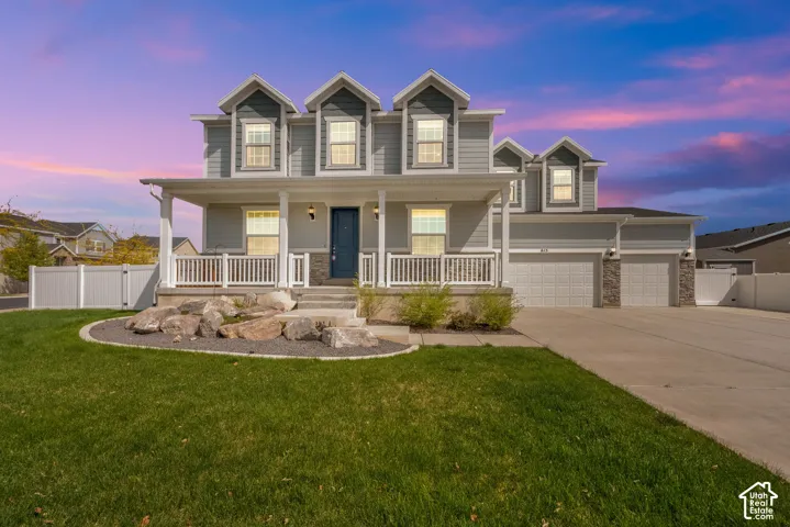 Traditional home featuring a porch, driveway, stone siding, a gate, and a garage