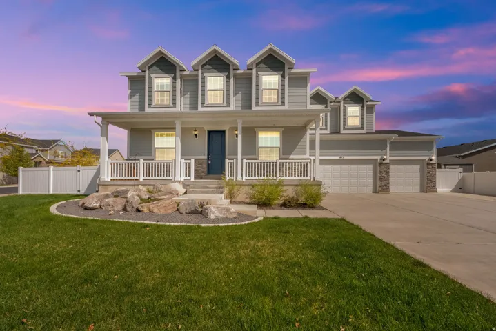 Traditional home featuring a porch, driveway, stone siding, a gate, and a garage