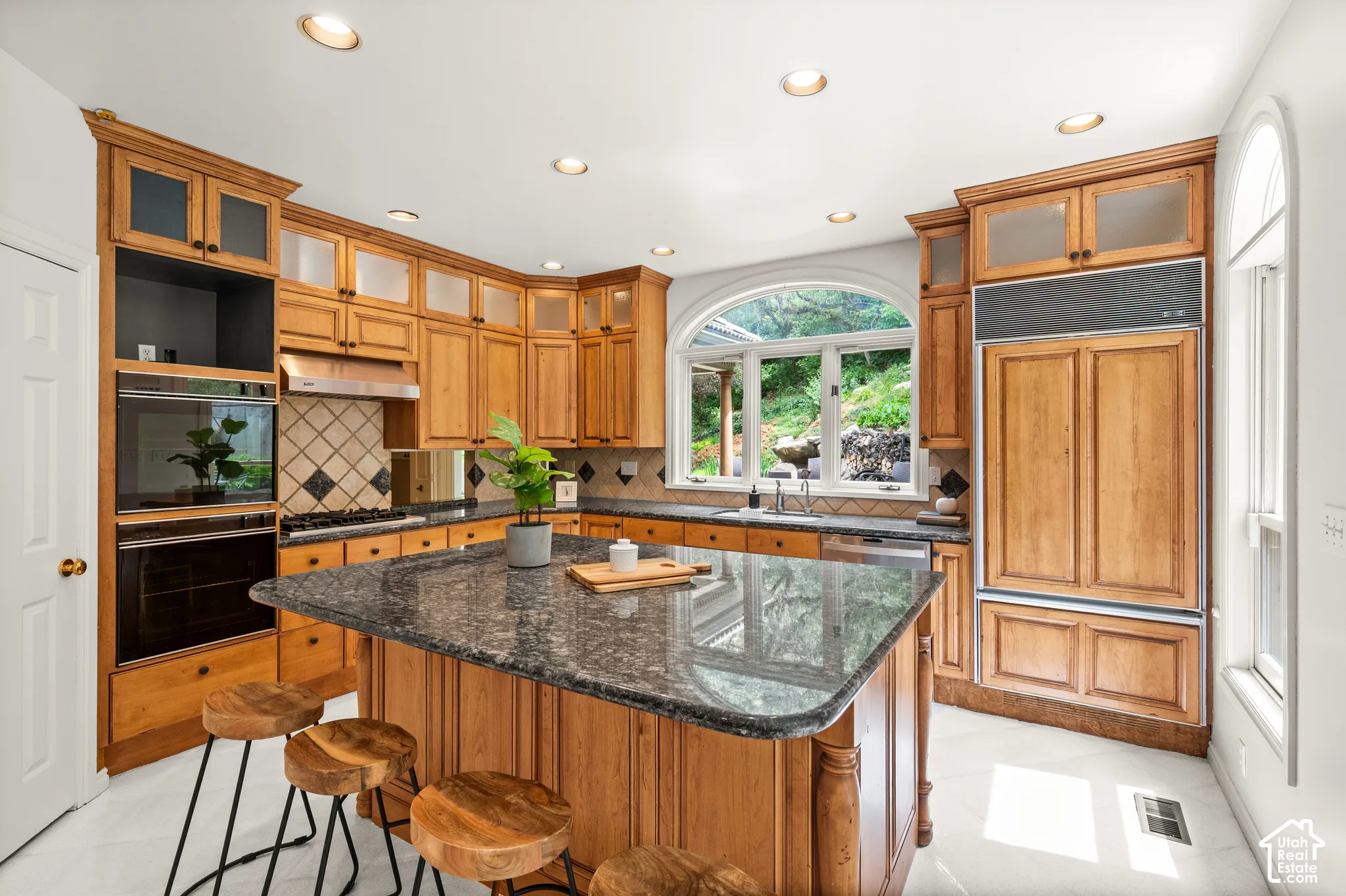 Kitchen featuring a central island with a stone countertop, extensive wood cabinetry, built-in double ovens, and an integrated panel-ready refrigerator
