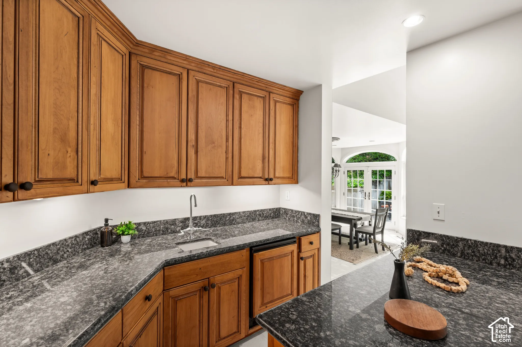Bar area featuring granite countertops, wood cabinetry with black hardware, a stainless steel sink.