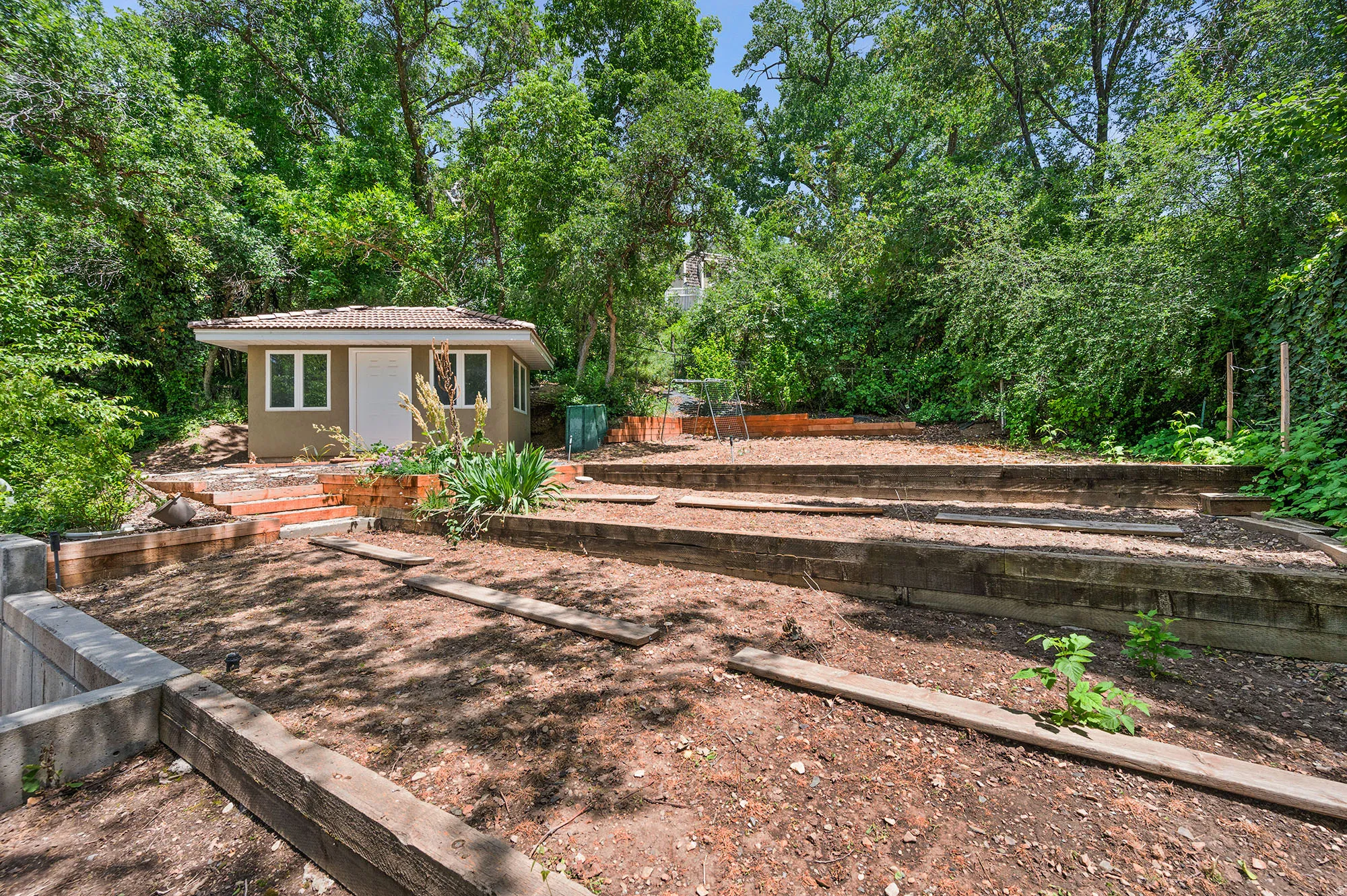 View of upper yard with an outbuilding, a vegetable garden, and view of wooded area