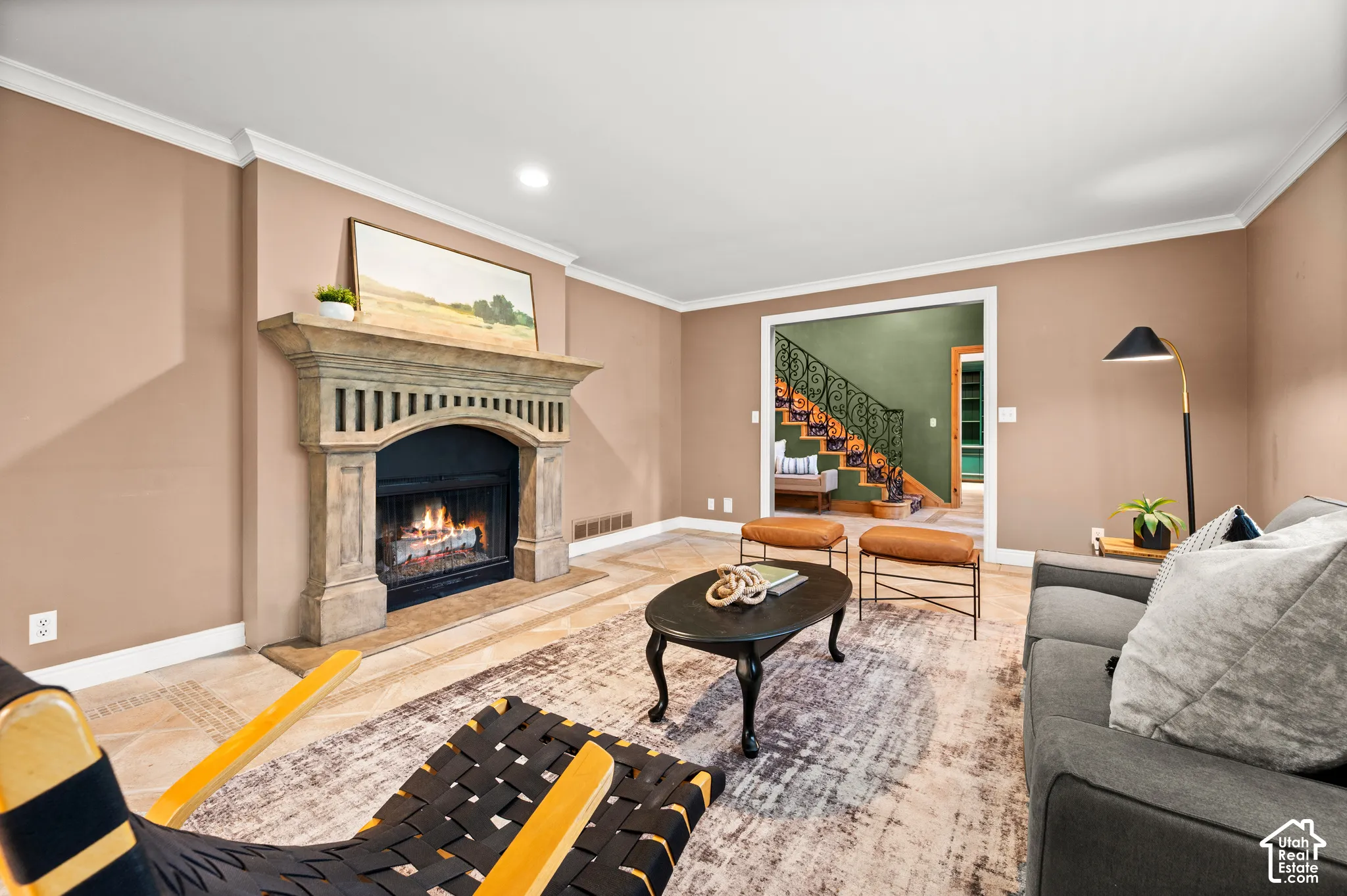 Living area featuring a detailed fireplace with a stone mantel, crown molding, and light-toned flooring