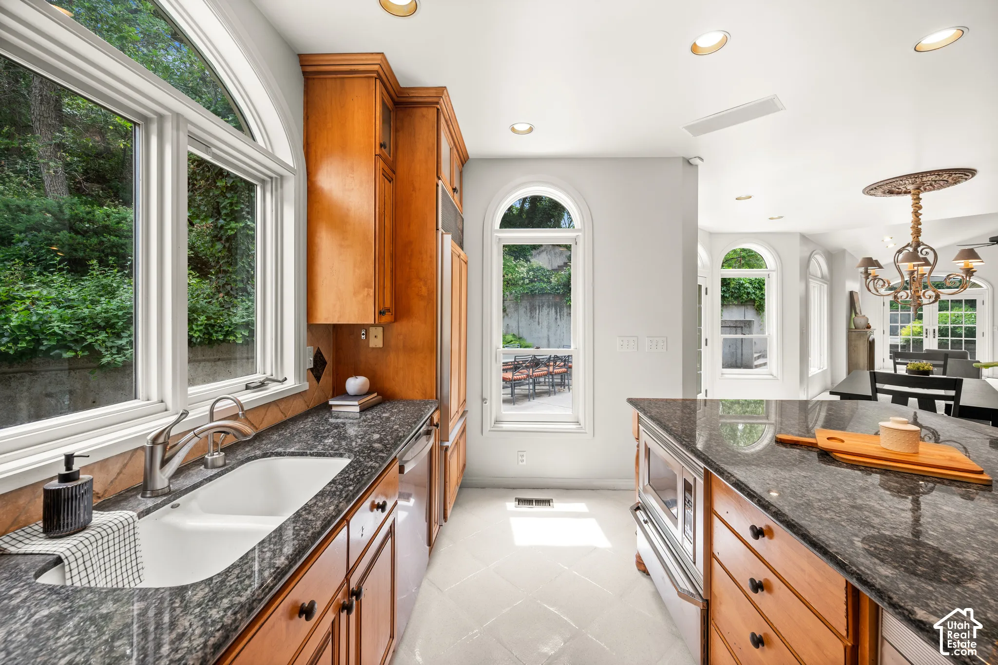 Kitchen featuring wood cabinetry, granite countertops, white tile flooring.