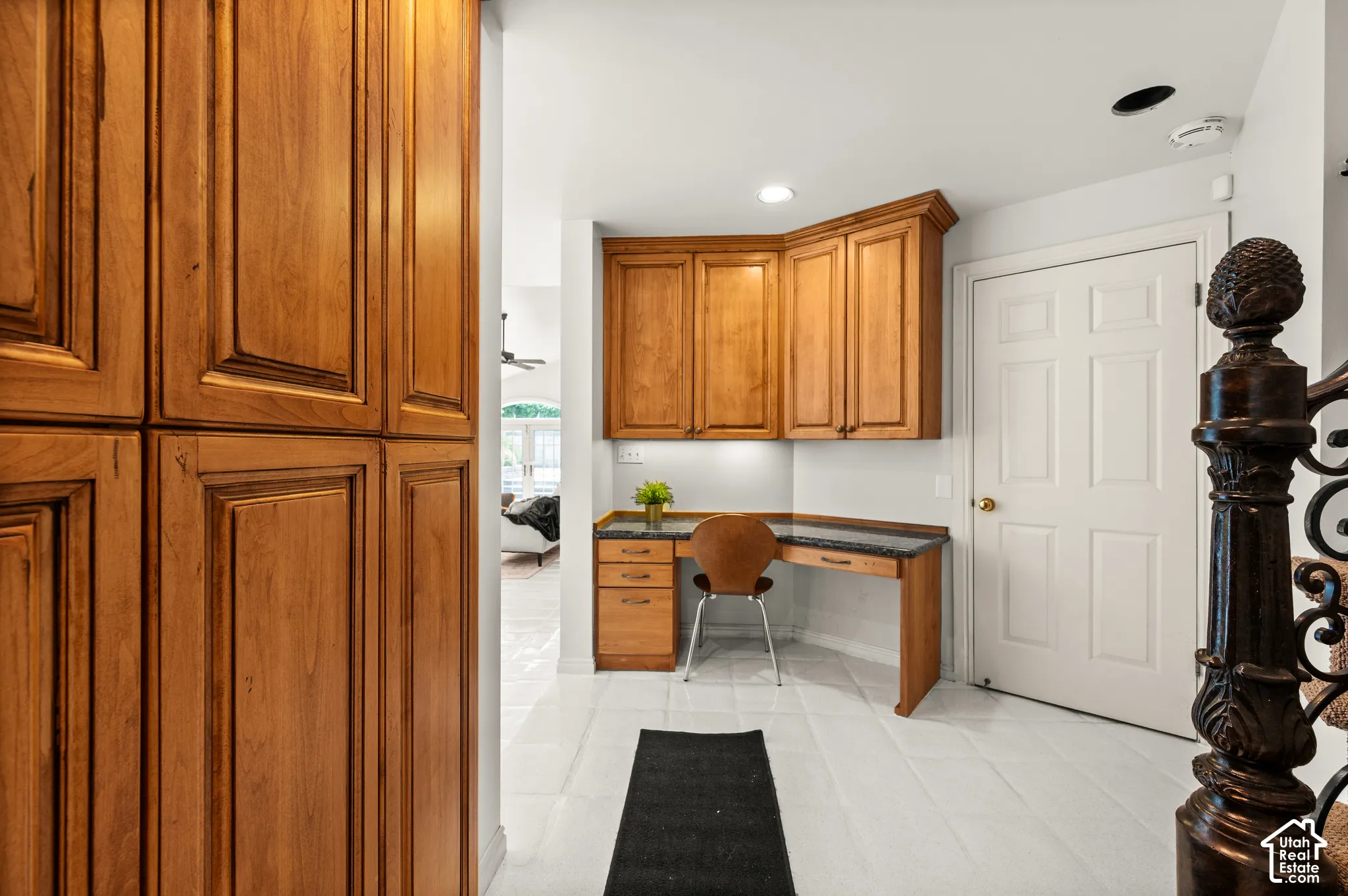 Built-in desk area featuring wood-finish cabinetry, dark stone-finish countertop, and more storage or pantry space.