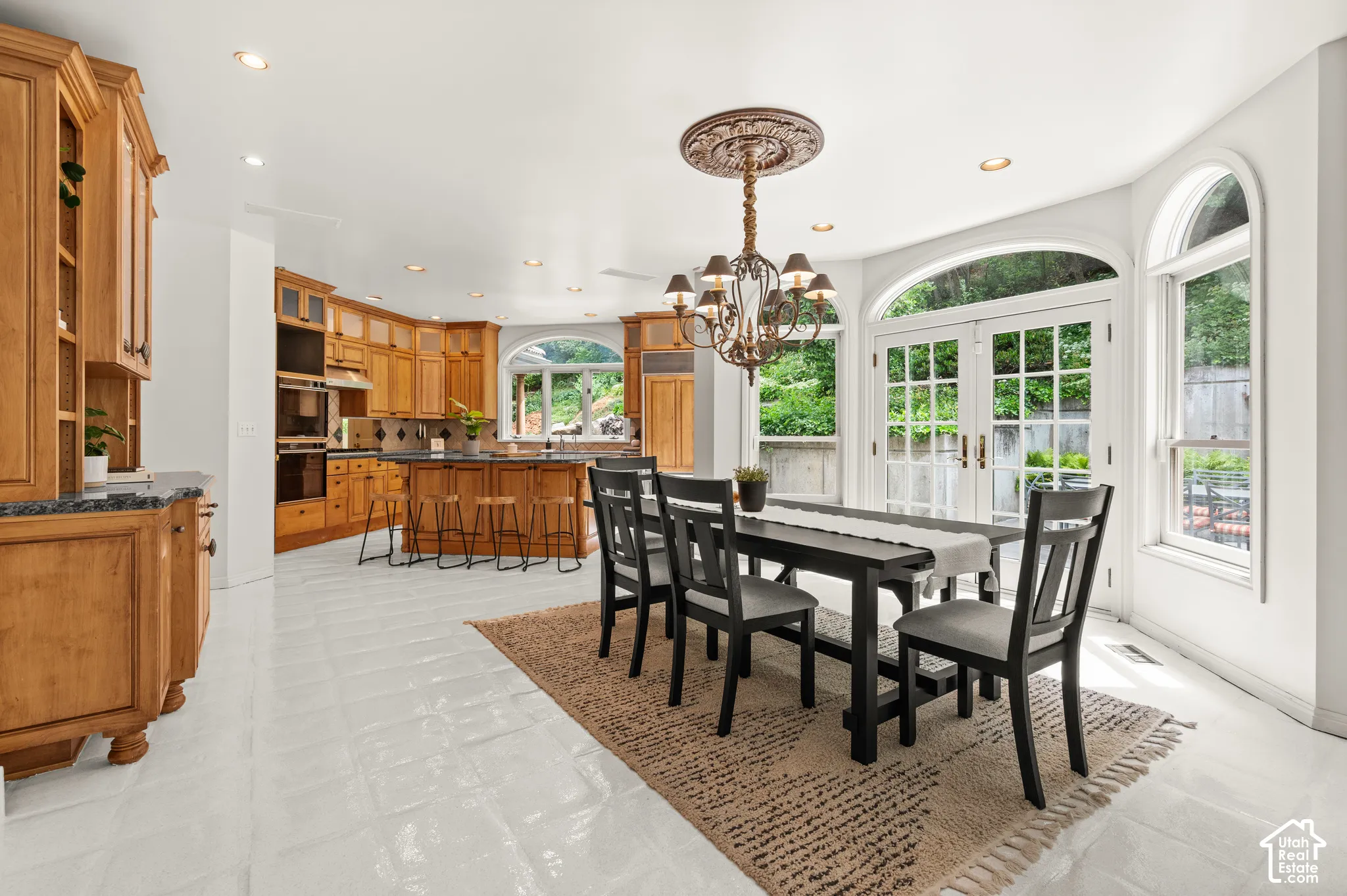Bright dining area with white tile flooring and double French doors opening to outdoor space