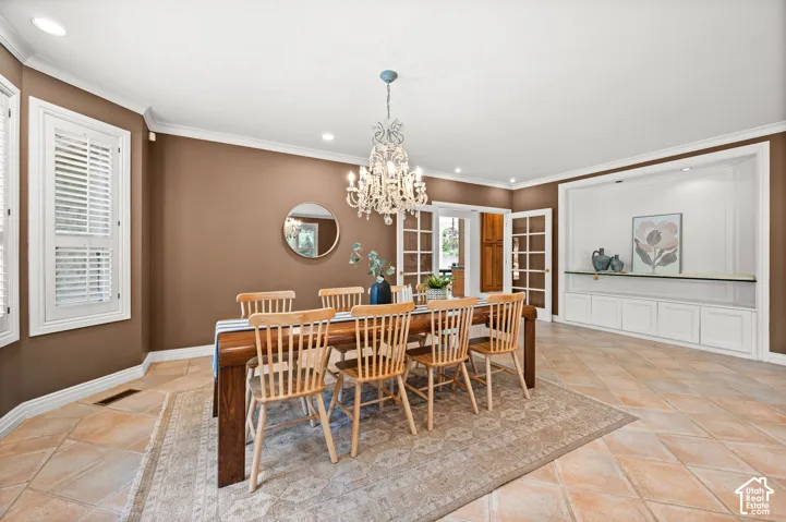 Spacious dining area featuring neutral tile flooring and crown molding