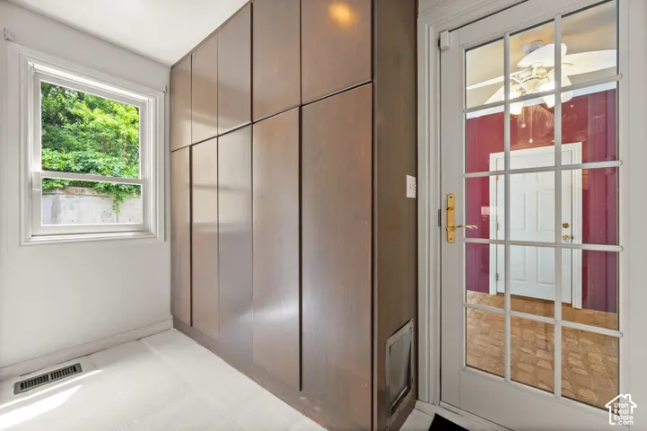 Built-in cabinetry with wood-finish panels, a single-hung window, and a glass-paned door with brass hardware