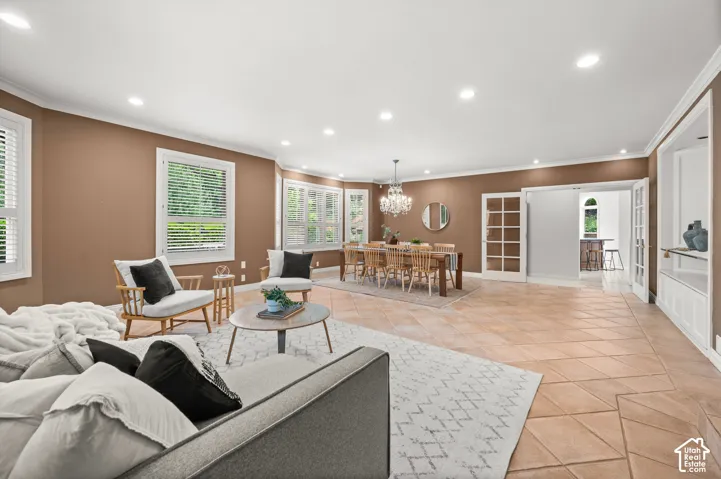 Spacious interior featuring a combination of tile flooring and an area rug, built-in shelving, recessed lighting, and multiple windows with white plantation shutters.