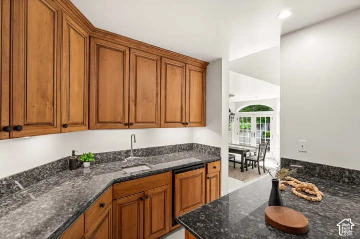 Bar area featuring granite countertops, wood cabinetry with black hardware, a stainless steel sink.