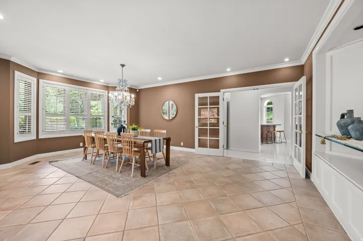 Spacious room featuring diamond-patterned floor tiling and a large bay window with plantation shutters