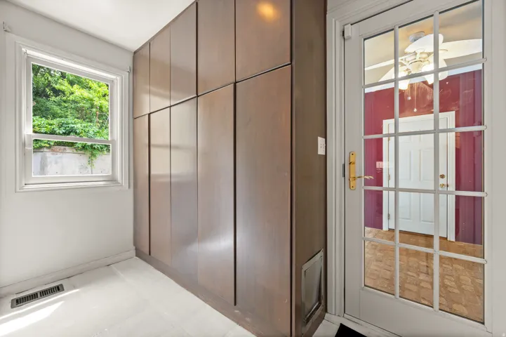 Built-in cabinetry with wood-finish panels, a single-hung window, and a glass-paned door with brass hardware