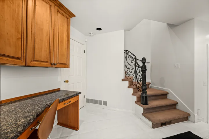 Built-in desk featuring a stone-finish countertop and wood cabinetry, 2nd set of stairs to upper level.