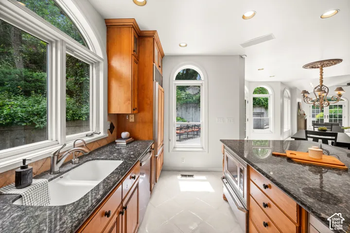 Kitchen featuring wood cabinetry, granite countertops, white tile flooring.