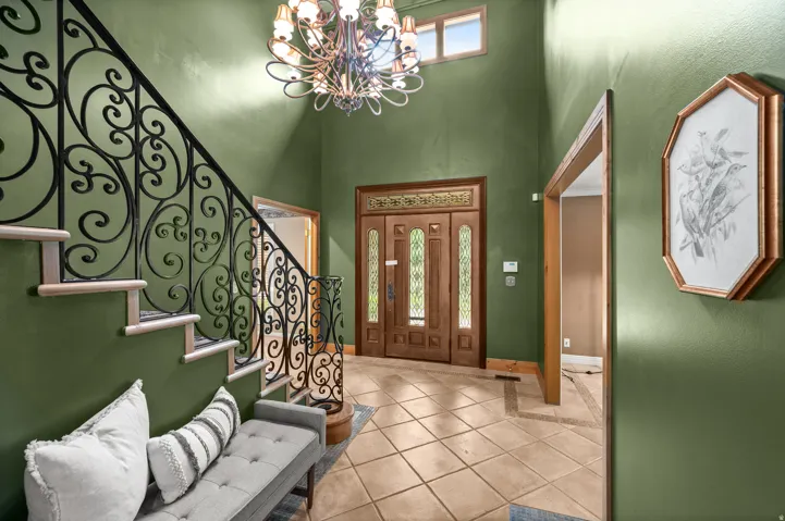 Grand foyer featuring a two-story ceiling, a decorative chandelier, and a wood-finish front door with glass panels