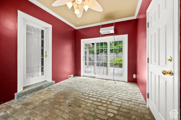 Room featuring brick-style flooring, red walls, and white crown molding & 2 doors.