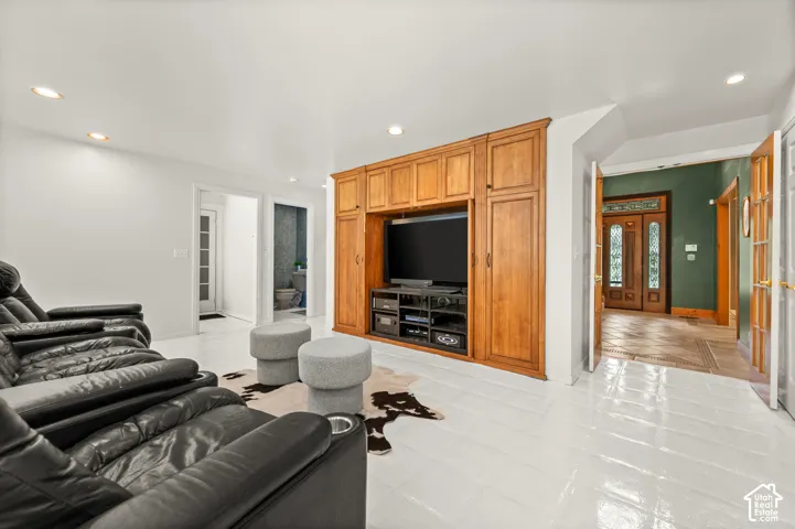 Entertainment room featuring white tiled flooring, a built-in wood-finish media center with integrated cabinetry, and recessed ceiling lighting