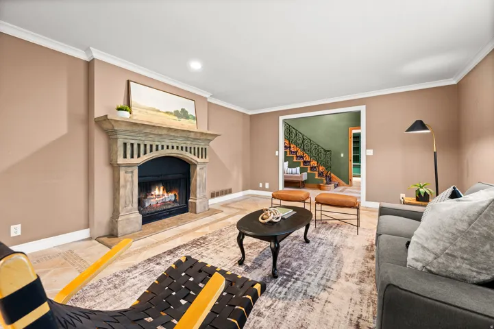 Living area featuring a detailed fireplace with a stone mantel, crown molding, and light-toned flooring