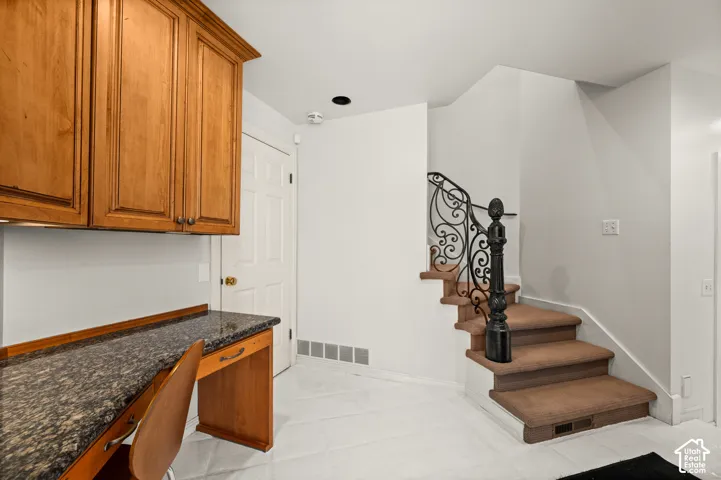 Built-in desk featuring a stone-finish countertop and wood cabinetry, 2nd set of stairs to upper level.