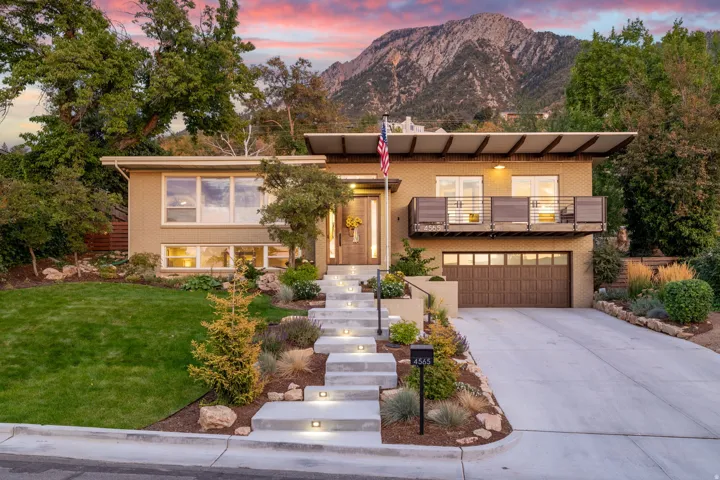 View of front facade with concrete driveway, a garage, a yard, and a mountain view