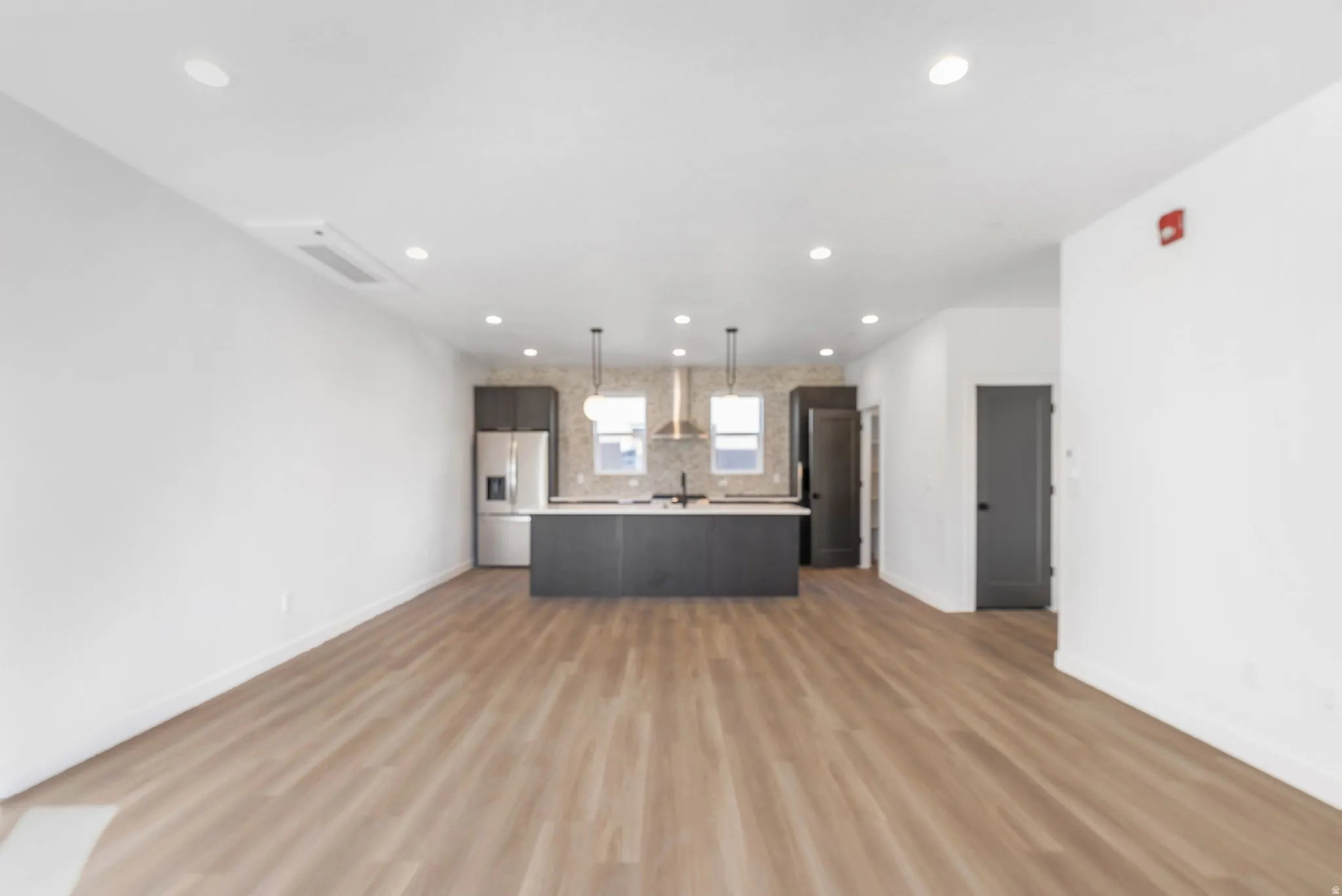 Photos are of a finished unit - Kitchen with open floor plan, light countertops, stainless steel fridge, a center island, and light wood-style floors