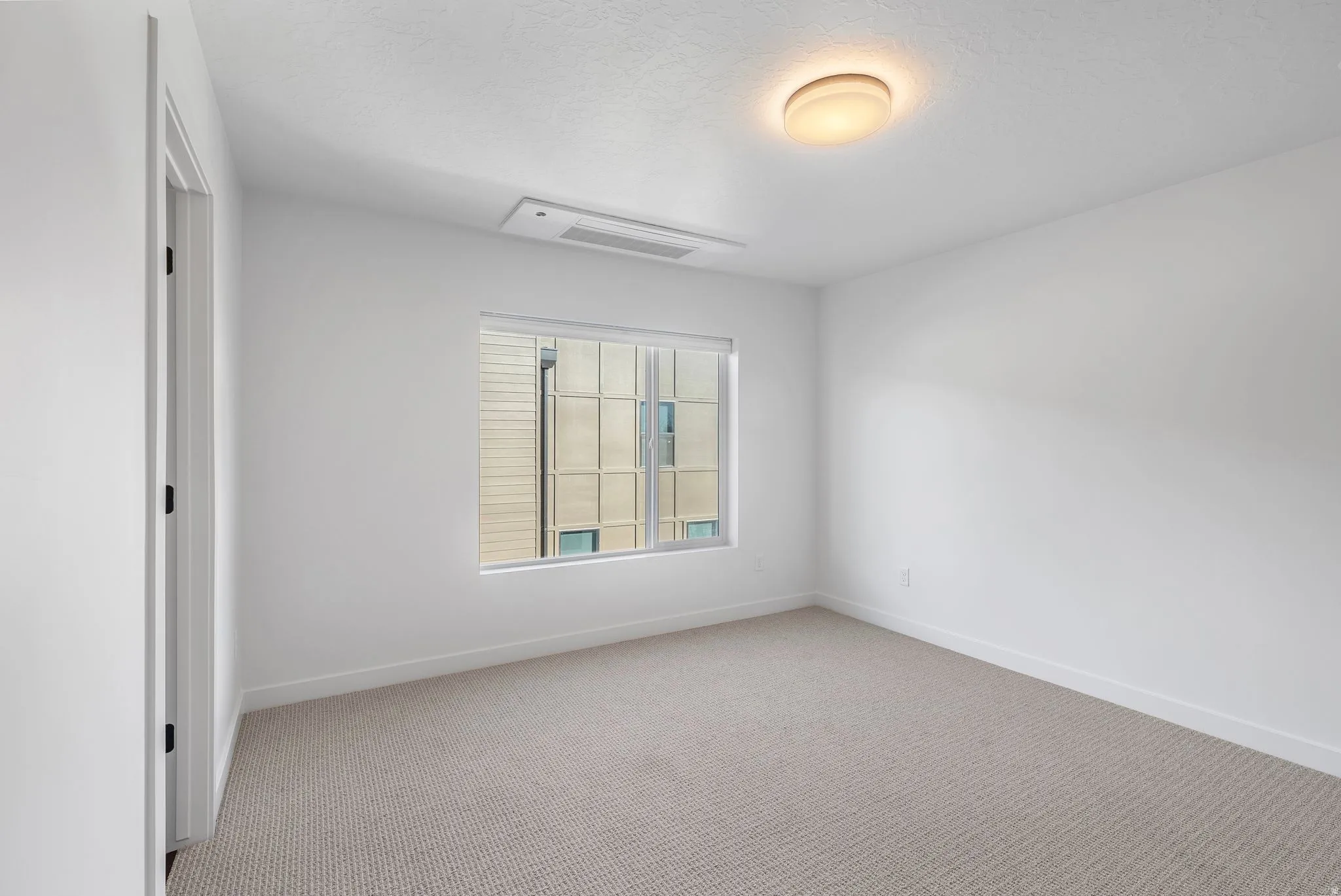 Photos are of a finished unit - Unfurnished room with light colored carpet and a textured ceiling