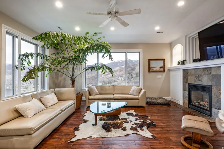 Living area with a ceiling fan, a tiled fireplace, hardwood / wood-style floors, and recessed lighting