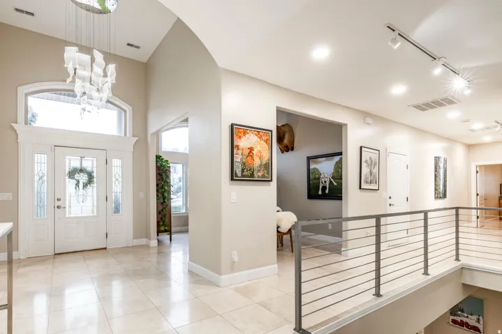 Foyer with rail lighting, light tile patterned floors, and a high ceiling