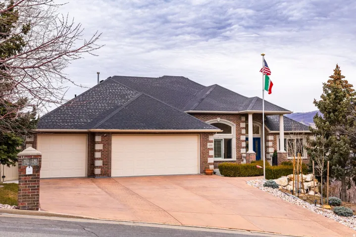 French country home featuring a garage, concrete driveway, roof with shingles, and brick siding