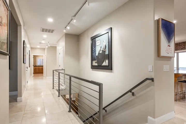 Hallway featuring an upstairs landing, light tile patterned flooring, and rail lighting