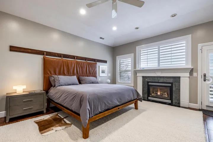 Bedroom featuring wood finished floors, a ceiling fan, a tile fireplace, recessed lighting, and access to exterior