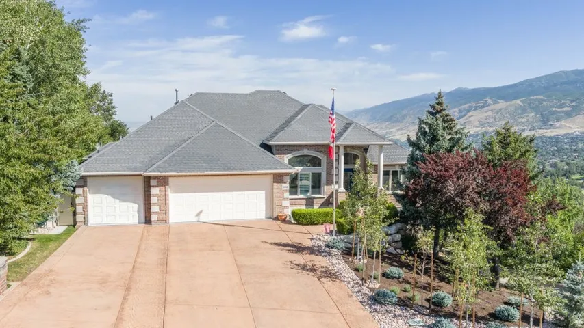 Brick and stucco facade with an attached three-car garage, dark shingle roofing, and a concrete driveway