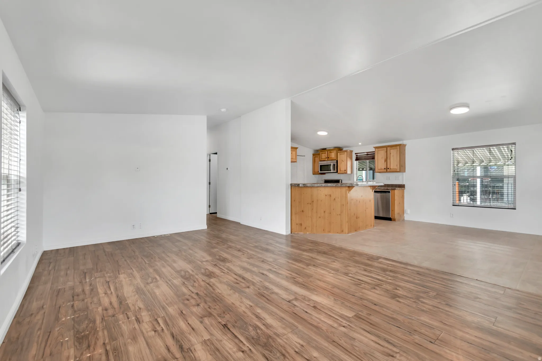 Unfurnished living room featuring light wood-style flooring and vaulted ceiling