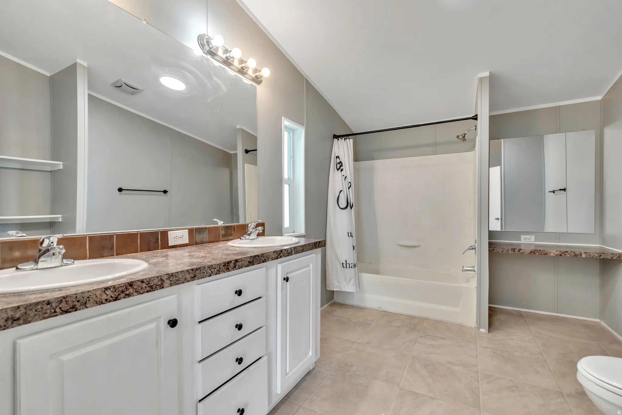 Full bath with double vanity, shower / bath combination with curtain, crown molding, and light tile patterned floors