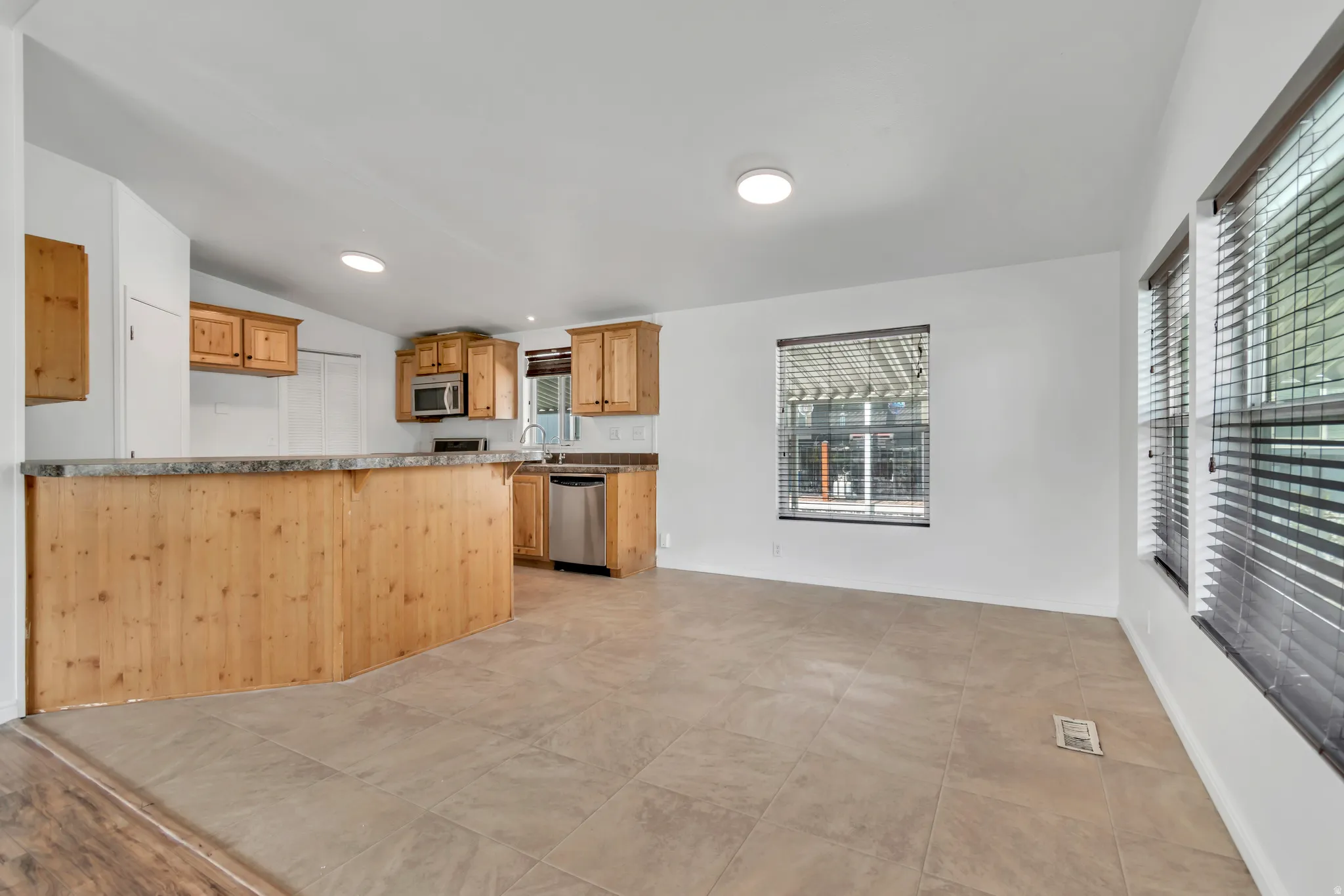 Kitchen with stainless steel appliances, vaulted ceiling, recessed lighting, and a peninsula