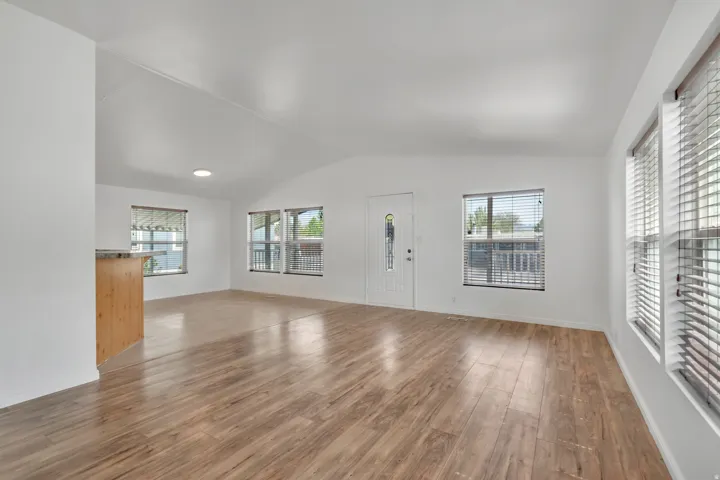 Unfurnished living room with vaulted ceiling and dark wood-style flooring
